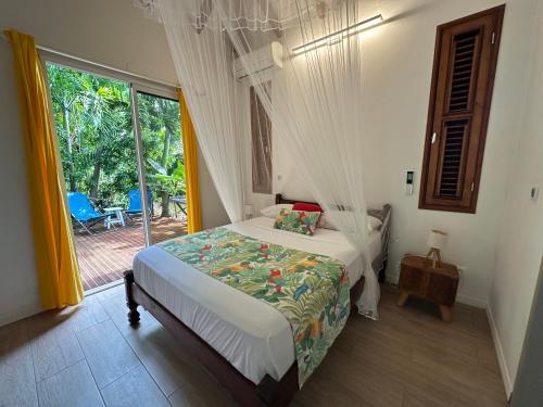 a bedroom with a bed and a large window at Titalee Lodge 3 Villas autour d'une piscine in Saint-François