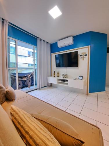 una grande camera da letto con una parete blu e una TV di Flat Blue Ponta Negra Beach a Natal