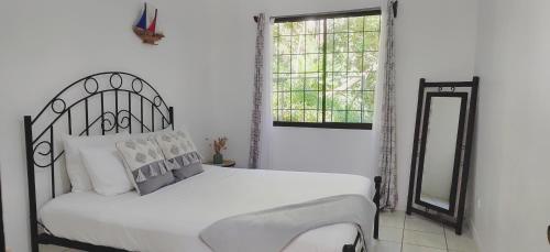 a white bedroom with a bed and a mirror at Casa Emma Quepos in Quepos