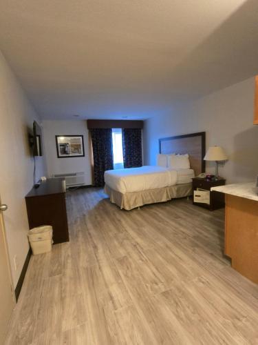 a large hotel room with a bed and wooden floors at Heritage Inn in Great Falls