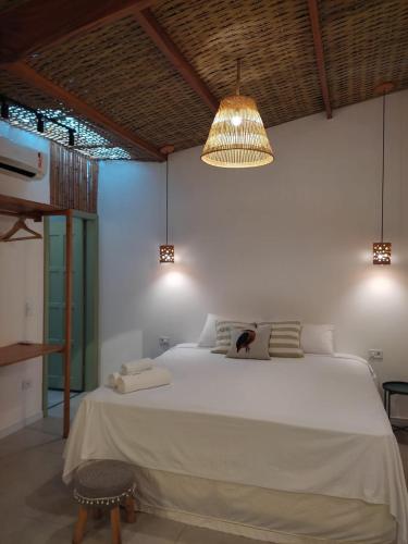 a bedroom with a large white bed and a chandelier at Casa mangarito - suítes in Ubatuba