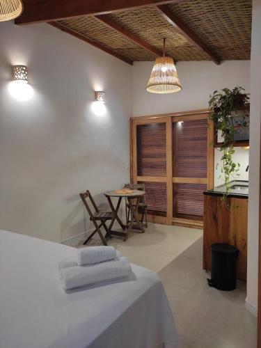 a room with a bed and a table with a tableablish at Casa mangarito - suítes in Ubatuba