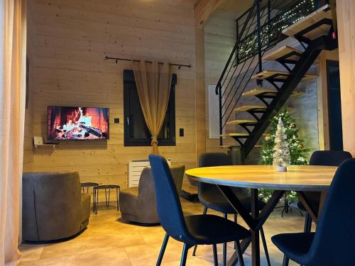 a dining room with a table and chairs and a tv at Les Chalets près de Chalain in Montigny-sur-lʼAin