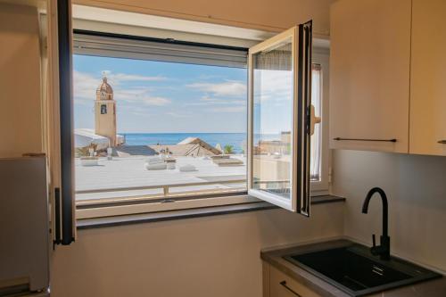 une fenêtre de cuisine donnant sur une tour d'horloge dans l'établissement Varicottis Luxury Apartments con parcheggio privato, à Varigotti