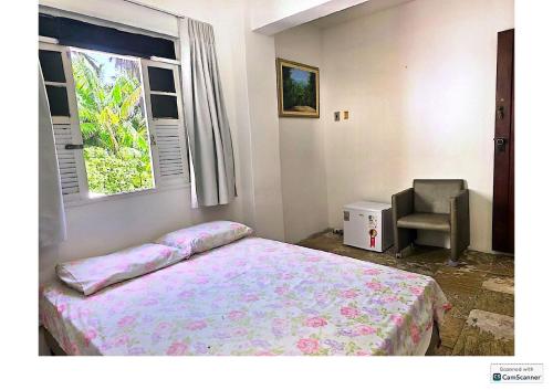 a bedroom with a bed and a chair and a window at Quinta do Conde in Lauro de Freitas