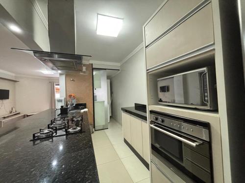 eine Küche mit Herd und Mikrowelle in der Unterkunft Ap Pertinho do Mar! in Balneário Camboriú