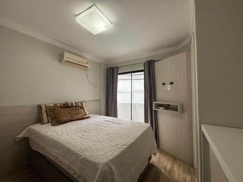 ein kleines Schlafzimmer mit einem Bett und einem Fenster in der Unterkunft Ap Pertinho do Mar! in Balneário Camboriú