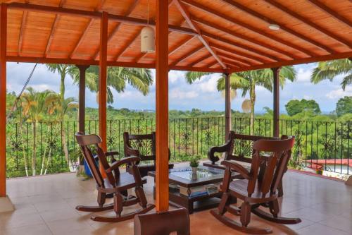 a porch with chairs and a table and a fence at Finca Hotel Andaquies in Armenia
