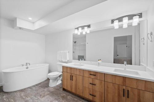 a bathroom with a tub and a sink and a toilet at Luxurious Large 3 Bedroom Loft Saskatchewan Drive in Edmonton