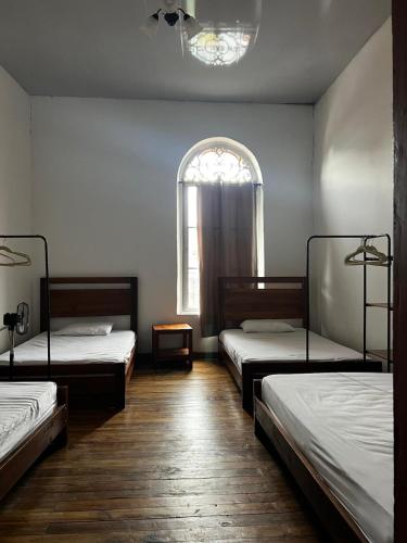 a room with three beds and a window at Casa-Hostal La Casona in Roldanillo
