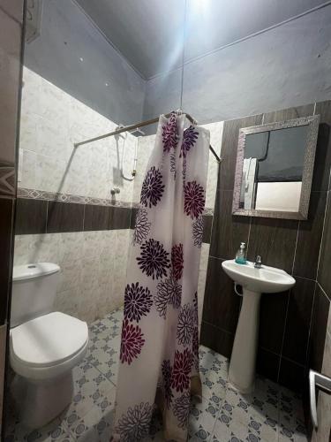 a bathroom with a toilet and a sink and a shower curtain at Casa-Hostal La Casona in Roldanillo