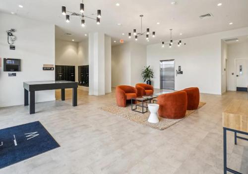 a living room with a piano and orange chairs at Modern Downtown Detroit 2BR Retreat in Detroit