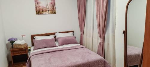 1 dormitorio con 1 cama con mantas y almohadas moradas en Pensiunea Terra Serenity, en Snagov
