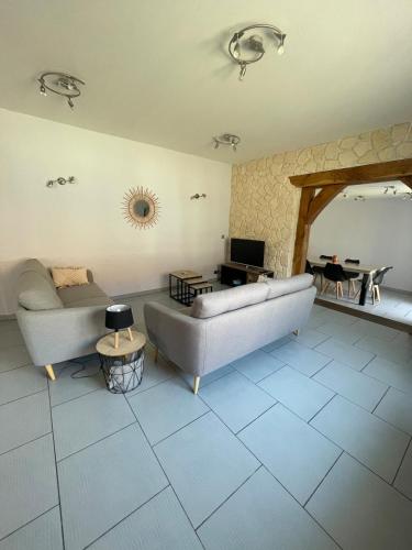 una sala de estar con un sofá y una mesa en La petite maison des bleuets, en Romorantin-Lanthenay