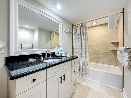 une salle de bains avec lavabo, miroir et baignoire dans l'établissement Waves 1, à St. Pete Beach