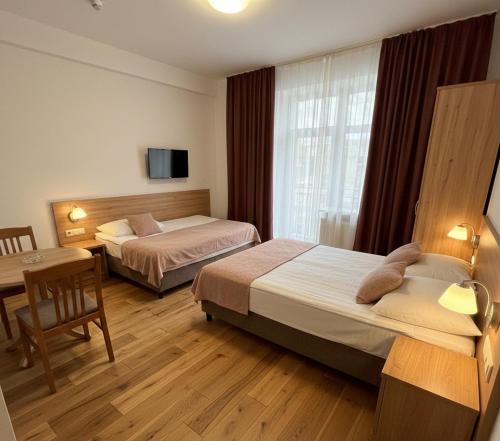 a hotel room with two beds and a table and a desk at Hotel Clina in Adana