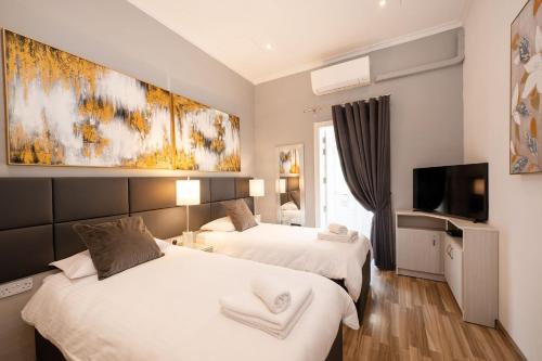 a hotel room with two beds and a tv at Valletta Apartments 19 in Valletta
