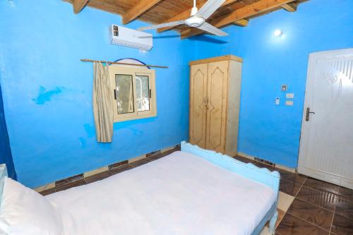 a blue bedroom with a bed and a window at Deja house in Luxor
