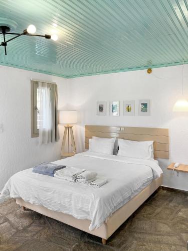a bedroom with a large bed with a blue ceiling at Panormos Beach Hotel Skopelos in Panormos Skopelos