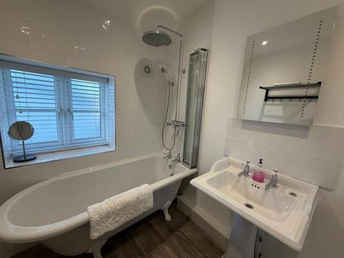 een witte badkamer met een bad en een wastafel bij Half Pint Cottage in Uplyme