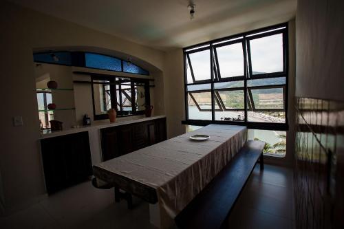 a dining room with a table and some windows at Casa com Vista para a Praia e Área Gourmet in São Sebastião