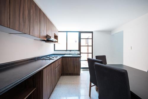 a kitchen with wooden cabinets and a black counter top at Residencias Santa Rosa de Viterbo 68 in Casa Blanca La Corregidora
