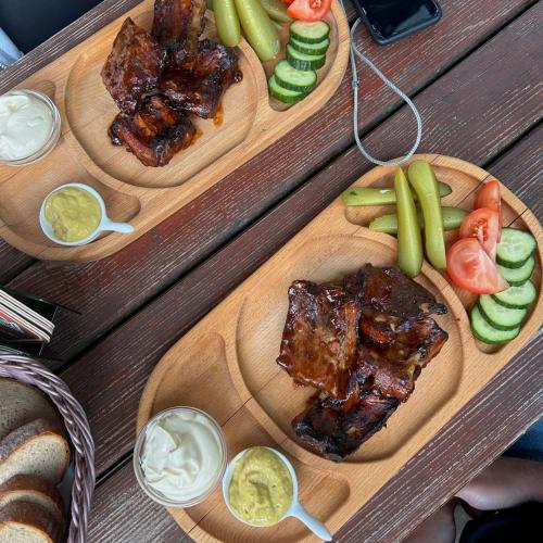 two wooden plates of food with meat and vegetables at Chata Hadimrška in Bartošovice v Orlických Horách