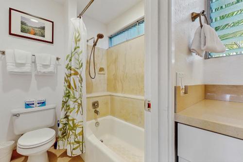 a bathroom with a toilet and a tub and a sink at SandPiper #116a in Princeville
