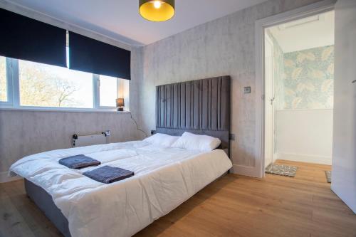 Spa & Rose Cottages Gilsland في Gilsland: غرفة نوم بسرير كبير مع نافذة كبيرة