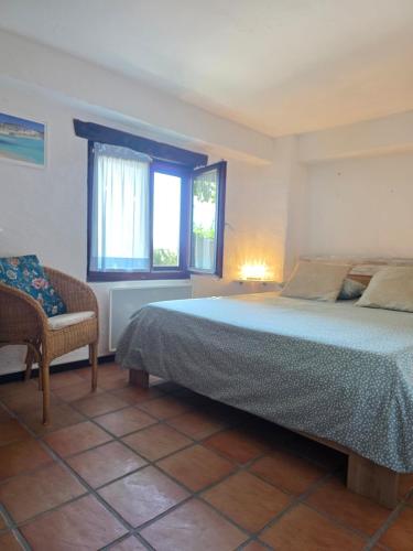 a bedroom with a bed and a chair and a window at Casa Leyian - Free parking in Brissago