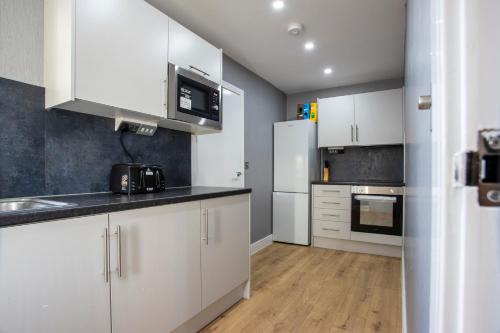 a kitchen with white cabinets and white appliances at Spa & Rose Cottages Gilsland in Gilsland