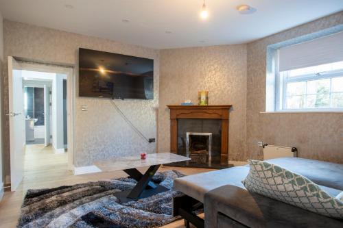 a living room with a couch and a fireplace at Spa & Rose Cottages Gilsland in Gilsland
