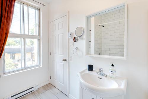 a white bathroom with a sink and a mirror at AFRICA - SelfCheckIn - Plateau - St-Laurent in Montréal