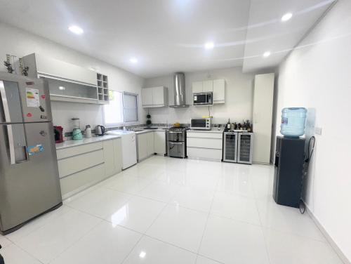 een grote keuken met witte vloeren en roestvrijstalen apparaten bij Casa moderna en barrio in Villa Ángela