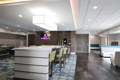 a lobby with a bar with yellow chairs at Garner Hotel Glen Burnie BWI Airport Area by IHG in Glen Burnie