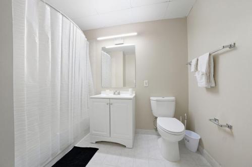 a white bathroom with a toilet and a sink at Relaxing studio perfect for extended visits in New Haven