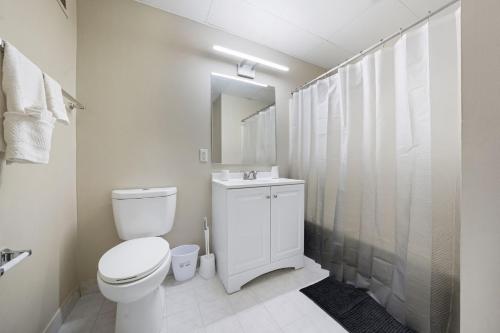 a white bathroom with a toilet and a sink at Homey studio perfect for long-term guests in New Haven