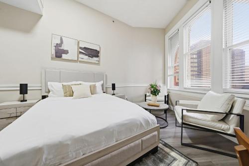 a white bedroom with a large bed and a chair at Homey studio perfect for long-term guests in New Haven