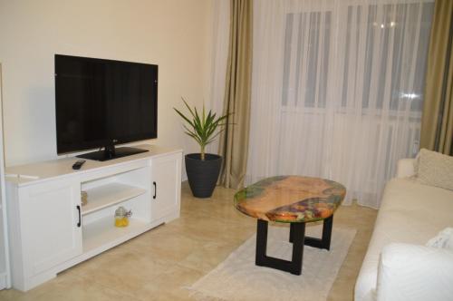 a living room with a television on a white cabinet at Iza Suite in Craiova