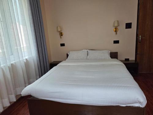 a large white bed in a room with a window at Pahaad Ko Ghaar in Nagarkot