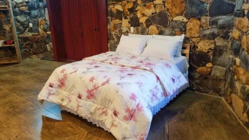 a bed in a room with a stone wall at SIG - Rancho Desiam - Serra Gaúcha in Gramado