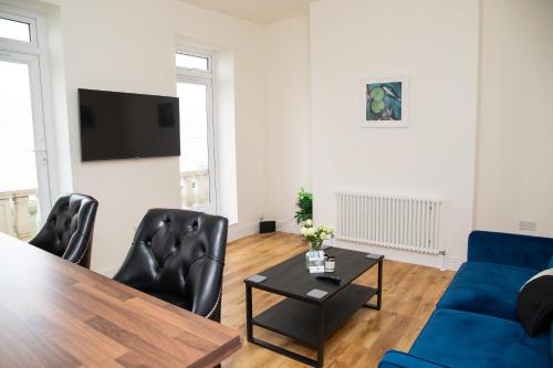 a living room with a table and a blue couch at Seaview Apartments - 28-29 Marine Parade, Harwich - Perfect for business & long term stays in Dovercourt
