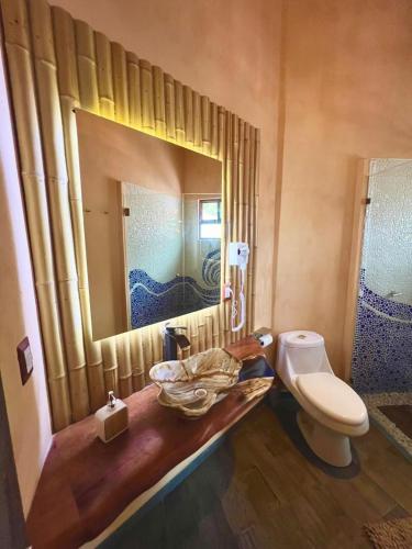 a bathroom with a sink and a toilet and a mirror at Bambu Villas Wellness Center in Amatlán