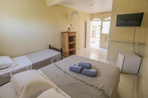 a room with two beds and a tv on the wall at Casa Maju Suites in Búzios