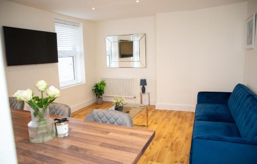 a living room with a blue couch and a table at Seaview Apartments - 28-29 Marine Parade, Harwich - Perfect for business & long term stays in Dovercourt