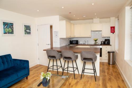a kitchen with a blue couch and bar stools at Seaview Apartments - 28-29 Marine Parade, Harwich - Perfect for business & long term stays in Dovercourt