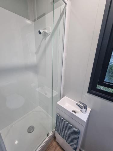 a white bathroom with a shower and a sink at Gore Bay View, Tiny Pod, Treehouse in Gore Bay