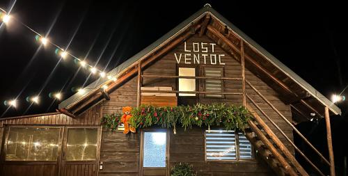 een huis met een verlicht bord aan de zijkant bij Cabana LoSt Ventoc in Vulcan