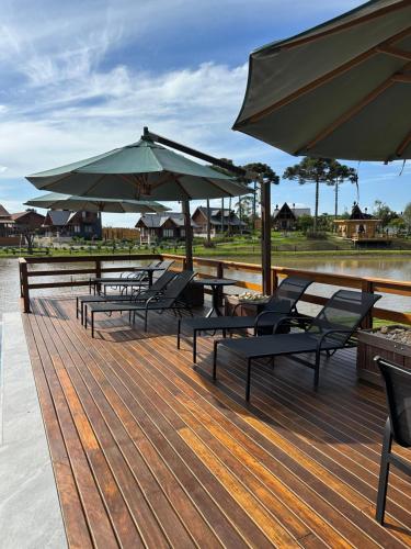 una terraza con mesas, sombrillas y sillas en Morada Das Grimpas, en Palmeira