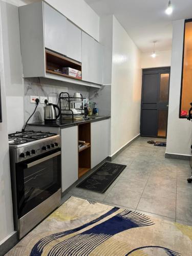 a small kitchen with a stove and white cabinets at BonBon Residency in Kiambu
